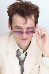 Image showing Artful businessman looks over eyeglasses crookedly grinning