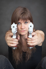 Image showing Young serious woman aims from two pistols