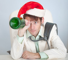 Image showing Drunk man in Christmas cap plays with bottle