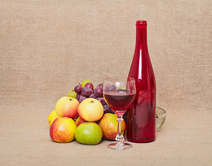 Image showing Still-life - red bottle and fruit against a canvas