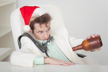 Image showing Drunken person in Christmas cap with bottle in a hand