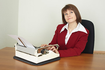 Image showing Young woman works on an ancient typewriter