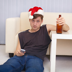 Image showing People in christmas hat sits on a floor with beer