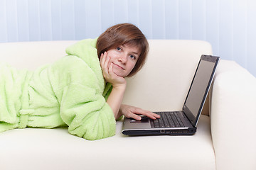 Image showing Young girl in green dressing gown on sofa with computer