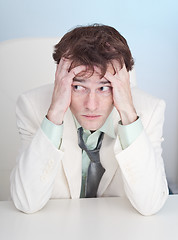 Image showing Uneasy businessman sits at a table