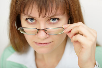 Image showing Young woman strictly looks over spectacles