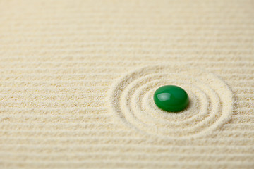 Image showing Green big glass drop on a sand surface