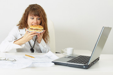 Image showing Businesswoman hurries up to eat without coming off work