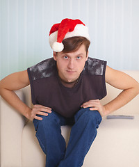 Image showing Person sits on sofa in a red Christmas cap