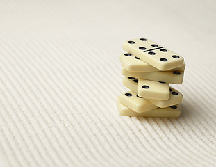 Image showing Dominoes pile on surface of sand - an abstract composition