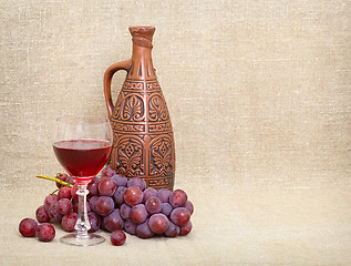 Image showing Clay jug with Georgian wine, glass and grapes