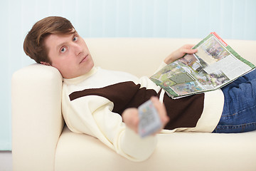 Image showing Man with newspaper and remote control