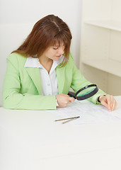 Image showing Young woman works with drawings by means of magnifier