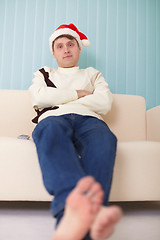 Image showing Person in Christmas cap sits on sofa