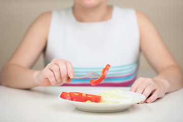 Image showing Woman eats vegetables keeping to strict vegetarian diet