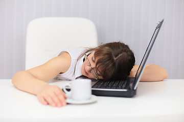 Image showing Young woman comically sleeps on laptop at office