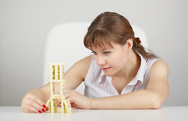Image showing Young woman plays from dominoes sitting at table
