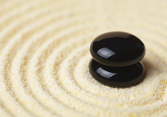 Image showing Two black stones put in a pile on sand