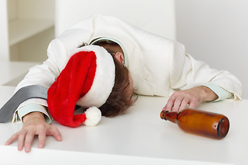 Image showing Strongly drunk man in Christmas cap on table