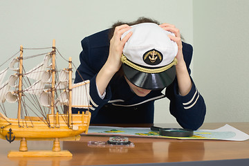 Image showing Woman in uniform of sea captain concentrated thinks over a map