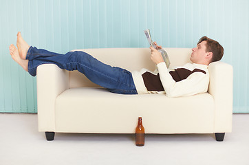 Image showing Person reads magazine comfortably lying on sofa
