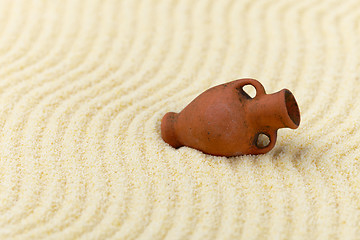 Image showing Ancient clay amphora on surface of yellow sand