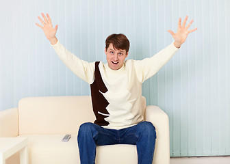 Image showing Young man exults sitting on sofa - sports fan