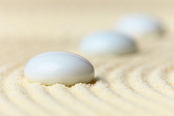 Image showing Three white drops on surface of yellow sand