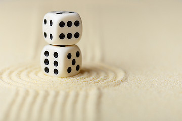 Image showing Two white dice with black dots on sand