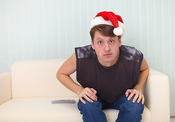 Image showing Person in Christmas cap sits on sofa and watches TV