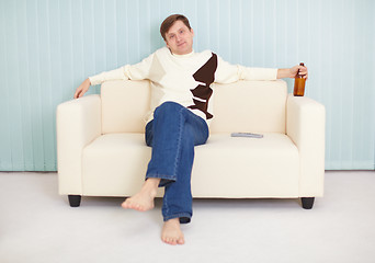 Image showing Young guy has rest on a sofa with beer and TV