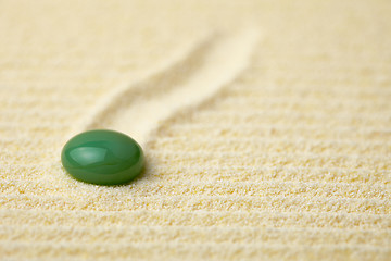 Image showing Green stone on a surface of yellow sand