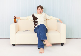 Image showing Man sits on sofa with beer bottle in a hand