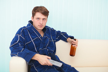 Image showing Guy sits on sofa and drinks beer looking TV