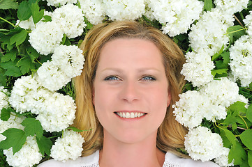 Image showing Young woman laying in flowers - snowballs