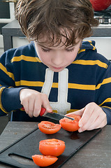 Image showing Boy cutting tomato