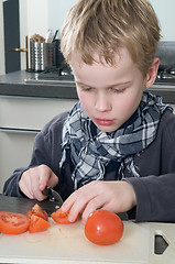 Image showing Boy cutting tomato