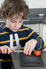 Image showing Boy cutting tomato