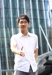 Image showing Asian Businessman offering for handshake, office building as bac