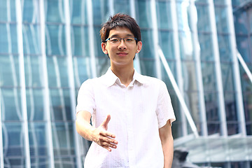 Image showing Asian Businessman offering for handshake, office building as bac