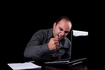 Image showing furious businessman looking to computer and taking notes