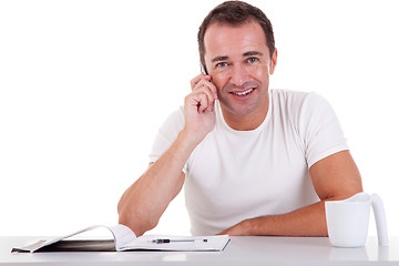 Image showing smiling middle-age man sitting at desk on the phone