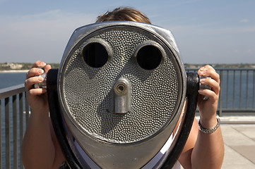 Image showing Woman looking through a coin operated binoculars