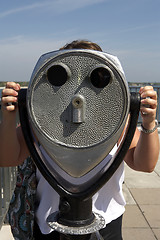 Image showing Woman looking through a coin operated binoculars