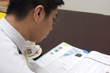 Image showing Young Asian Entrepreneur Reading Magazine