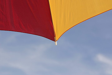 Image showing red and yellow parasol against a blue sky