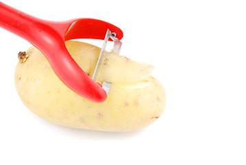 Image showing Peeling a potato with peeler on white