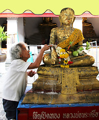 Image showing Thai woman putting gold on image of Buddha for good luck, Bangko