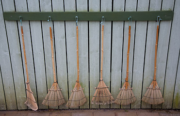 Image showing Six bamboo rakes on wall