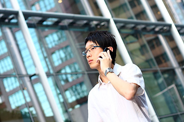 Image showing young businessman in a suit holding mobile phone in front of mod